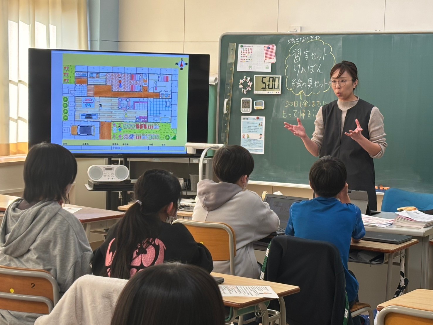建築士が黒板前で児童に説明する様子